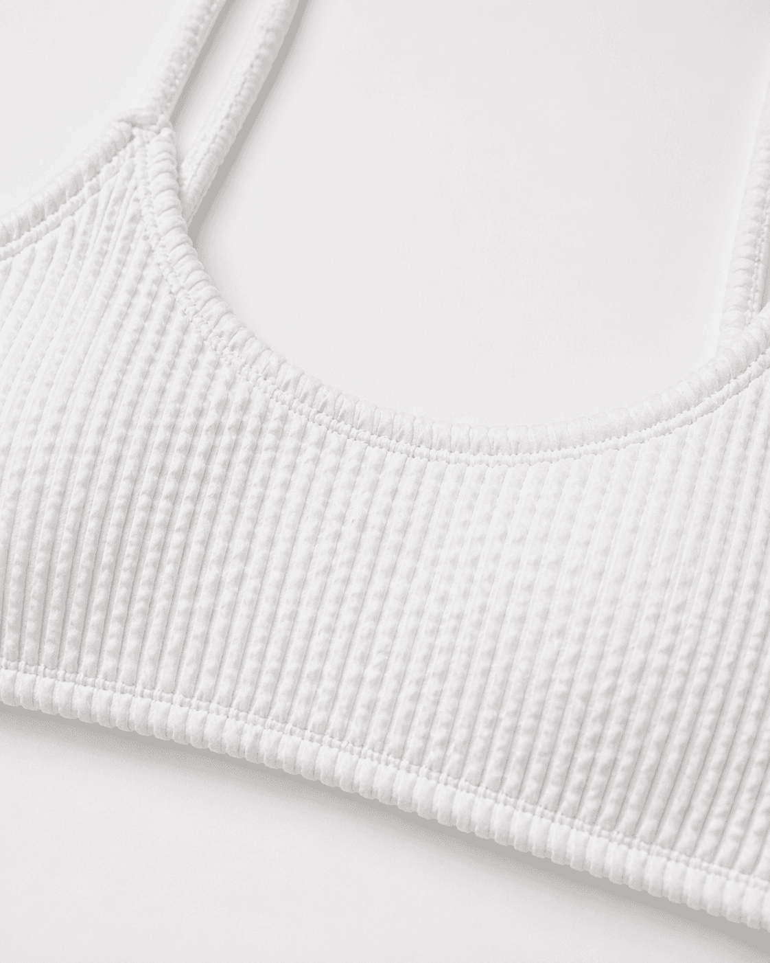 Close-up of a textured white bralette on a light gray background